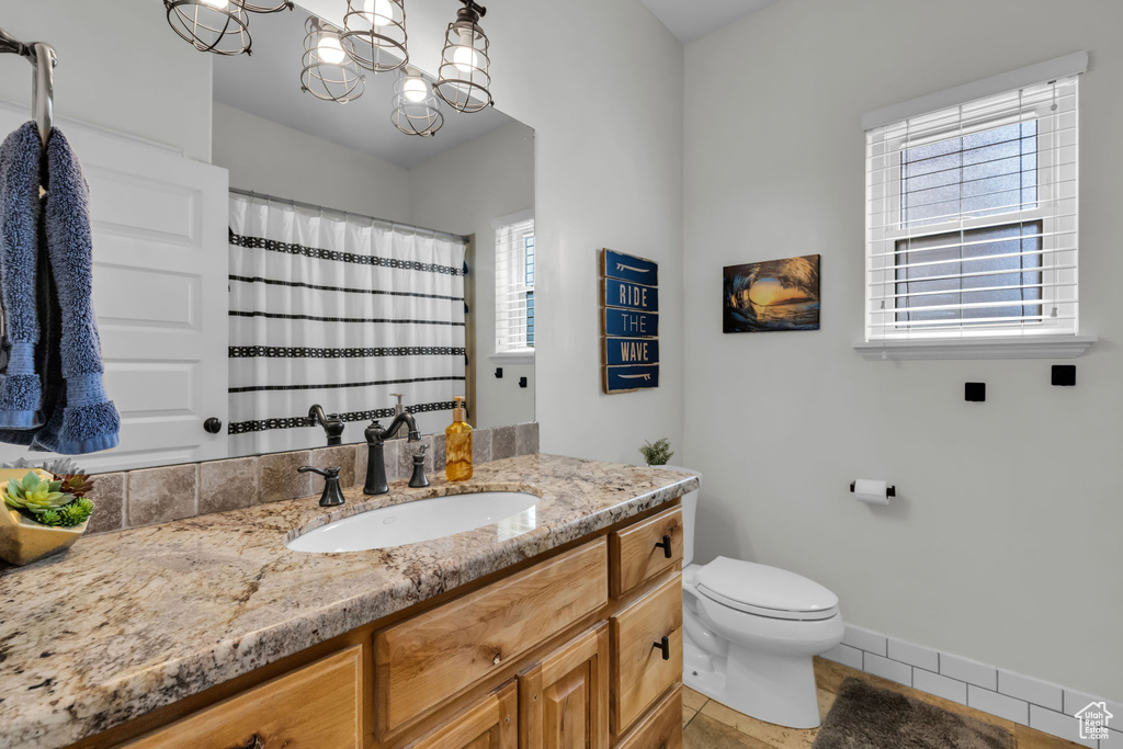 Bathroom with a notable chandelier, vanity, plenty of natural light, and toilet