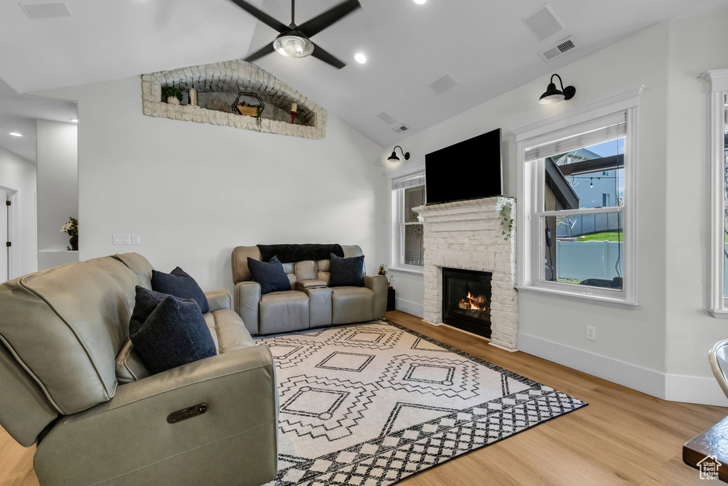 Living room with a stone fireplace, vaulted ceiling, hardwood / wood-style floors, and ceiling fan