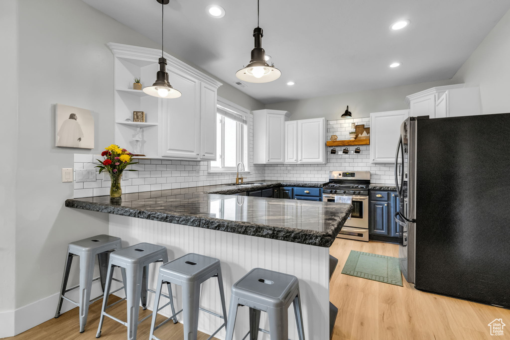 Kitchen featuring blue cabinets, white cabinets, stainless steel appliances, and kitchen peninsula