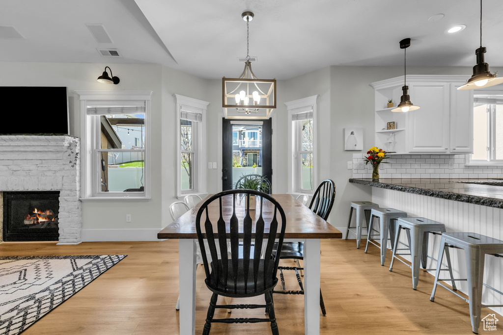 Dining space featuring light wood-type flooring, a stone fireplace, and a wealth of natural light