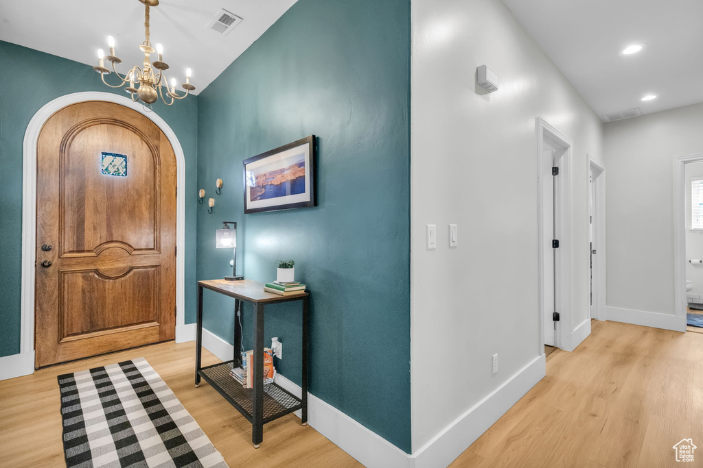 Foyer with light wood-type flooring and a chandelier