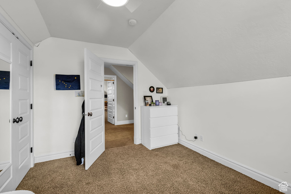 Unfurnished bedroom featuring lofted ceiling and carpet flooring