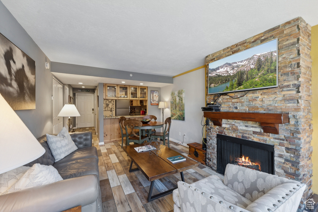 Living room with crown molding, a stone fireplace, and light hardwood / wood-style flooring