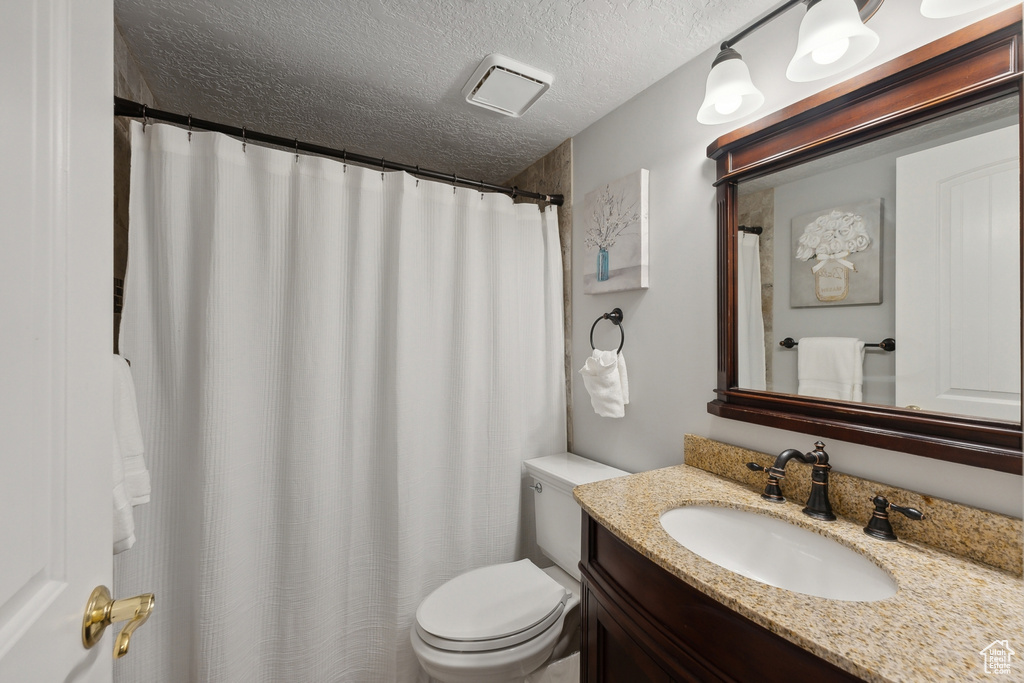 Bathroom featuring vanity, a textured ceiling, and toilet