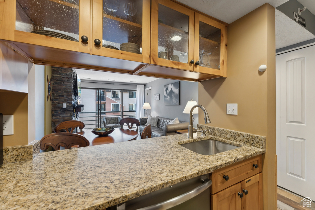 Kitchen featuring light stone countertops, stainless steel dishwasher, hardwood / wood-style floors, and sink