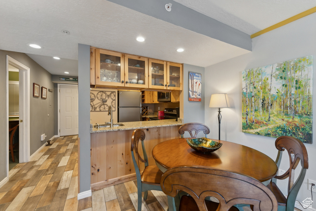 Dining area featuring a textured ceiling, light hardwood / wood-style floors, and sink