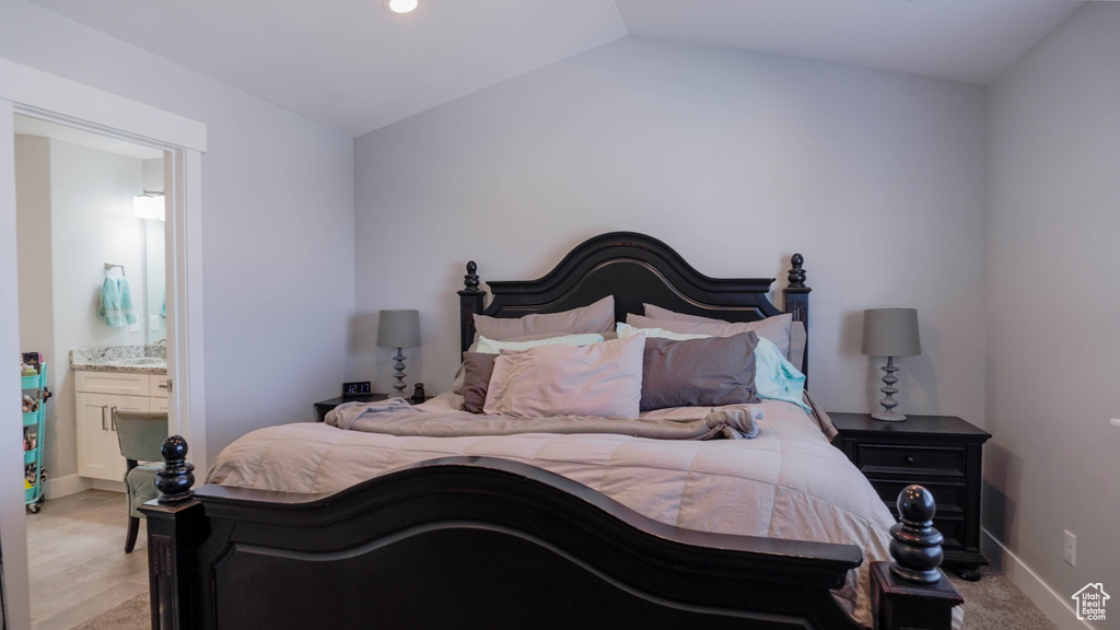 Bedroom featuring vaulted ceiling, light hardwood / wood-style floors, and ensuite bathroom