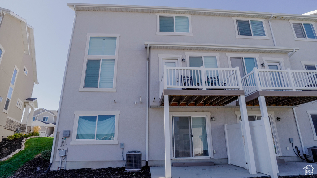 Back of property with a balcony, central AC unit, and a patio area