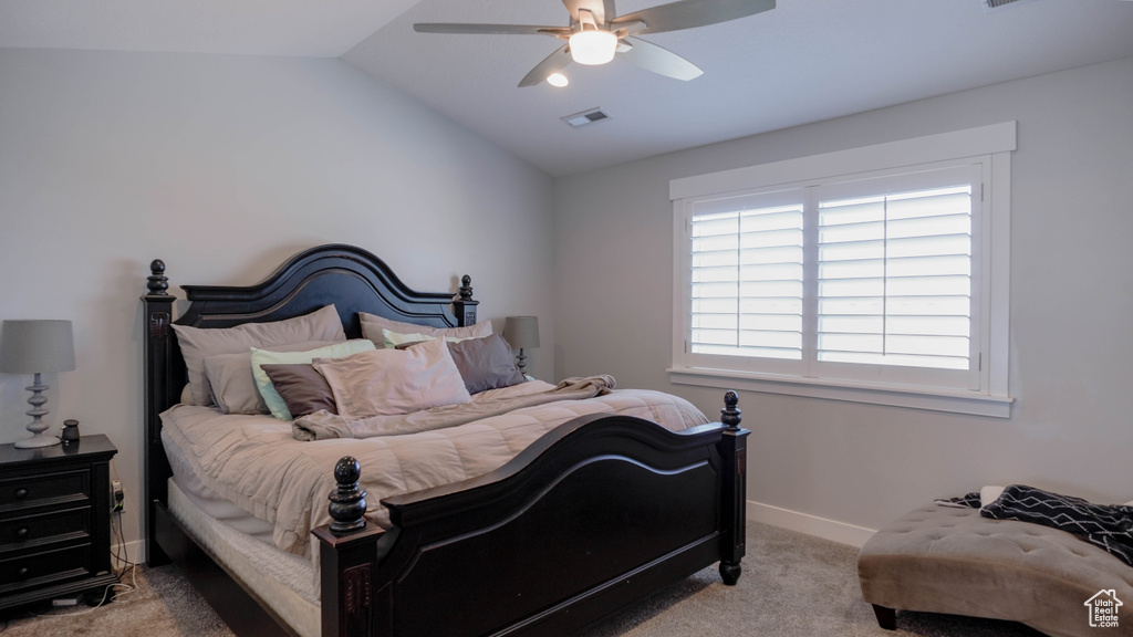 Carpeted bedroom featuring vaulted ceiling and ceiling fan