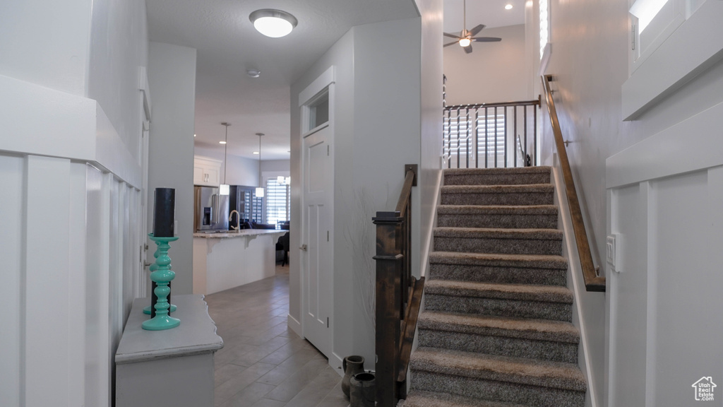 Stairway featuring a towering ceiling, hardwood / wood-style floors, ceiling fan, and sink