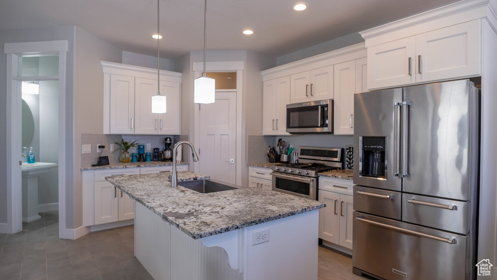 Kitchen with a center island with sink, white cabinetry, sink, and stainless steel appliances