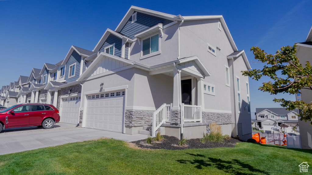 Multi unit property featuring covered porch, a front yard, and a garage