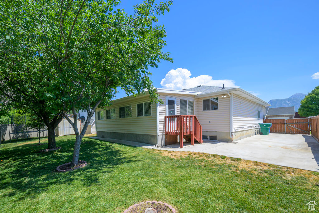 Back of property with a patio, a yard, and a mountain view