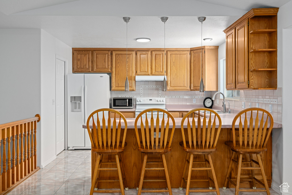 Kitchen with white appliances, decorative light fixtures, and backsplash