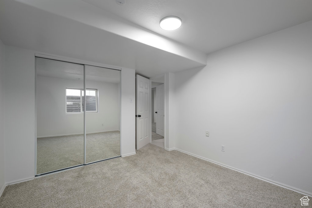 Unfurnished bedroom featuring a closet and light colored carpet