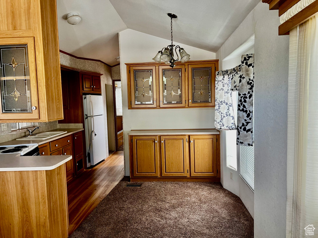 Kitchen featuring sink, vaulted ceiling, an inviting chandelier, white appliances, and decorative light fixtures