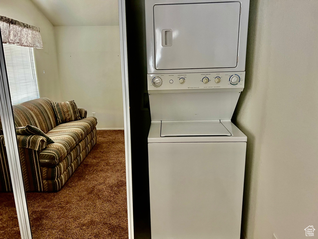 Washroom with stacked washer / drying machine and dark carpet