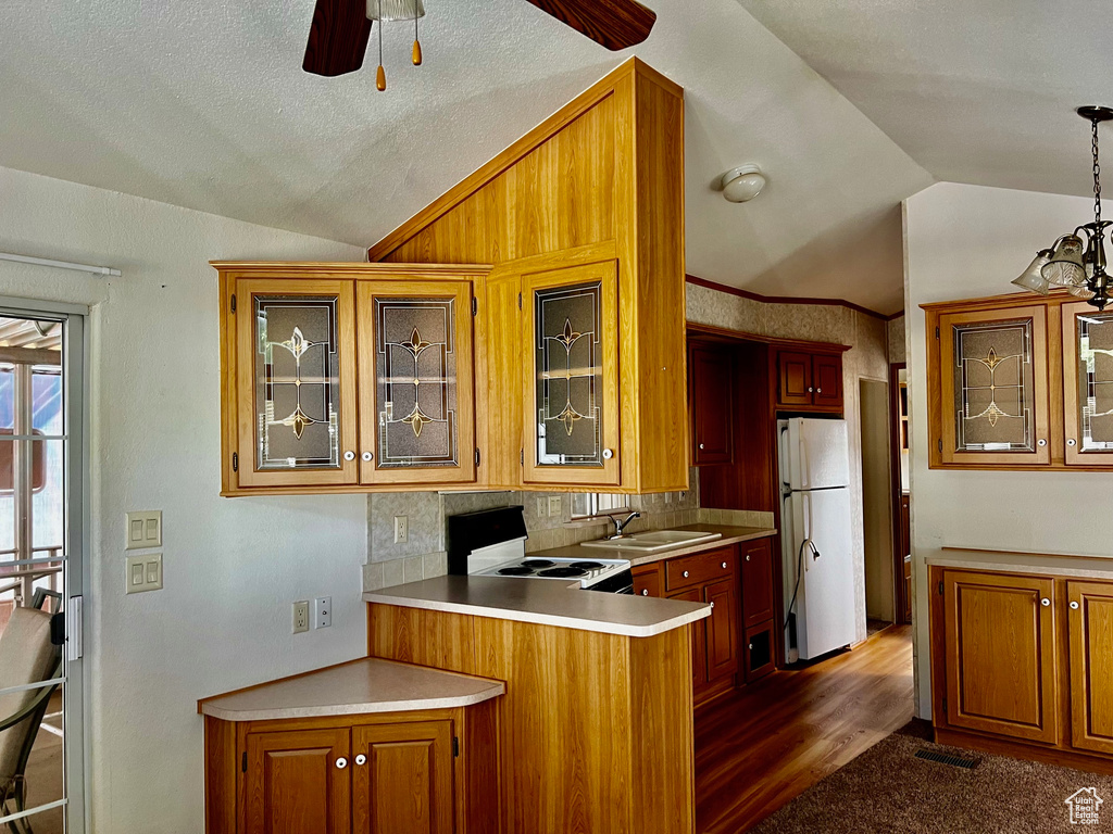 Kitchen with ceiling fan, pendant lighting, kitchen peninsula, white appliances, and vaulted ceiling