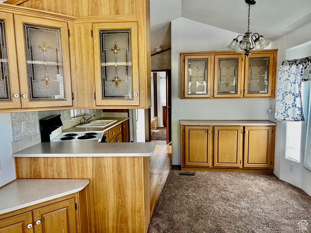 Kitchen featuring vaulted ceiling, pendant lighting, sink, light carpet, and a notable chandelier