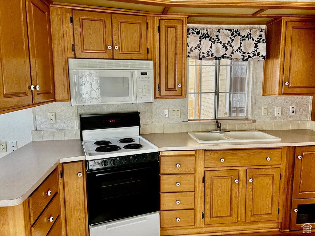 Kitchen featuring sink, white appliances, and decorative backsplash