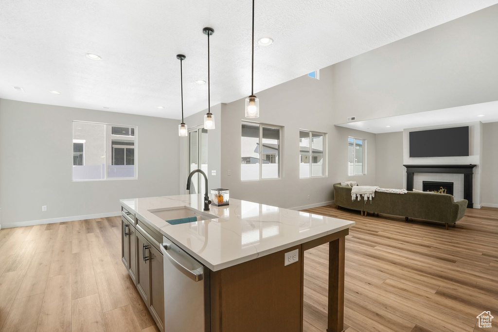 Kitchen featuring dishwasher, light hardwood / wood-style floors, sink, a center island with sink, and decorative light fixtures