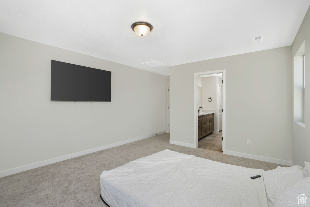 Bedroom with sink, light carpet, and ensuite bathroom