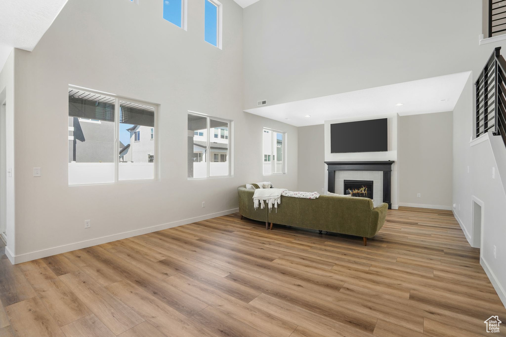 Unfurnished living room featuring a wealth of natural light, a high ceiling, and light wood-type flooring