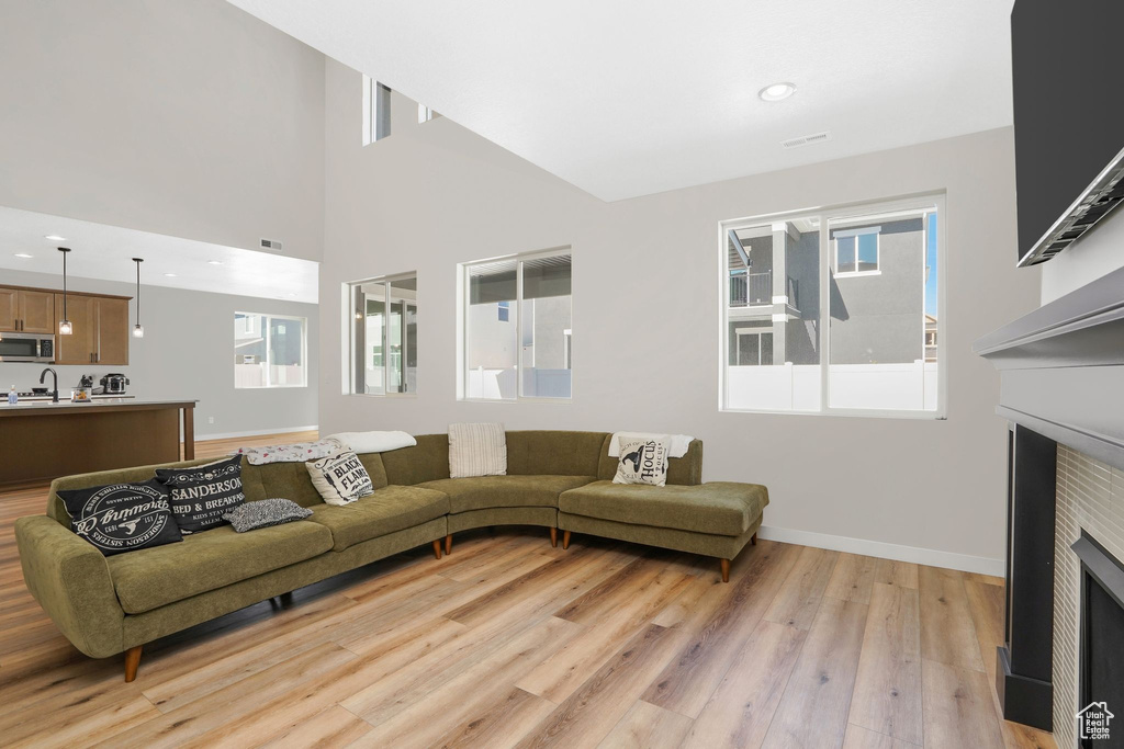 Living room featuring light hardwood / wood-style floors, sink, and high vaulted ceiling