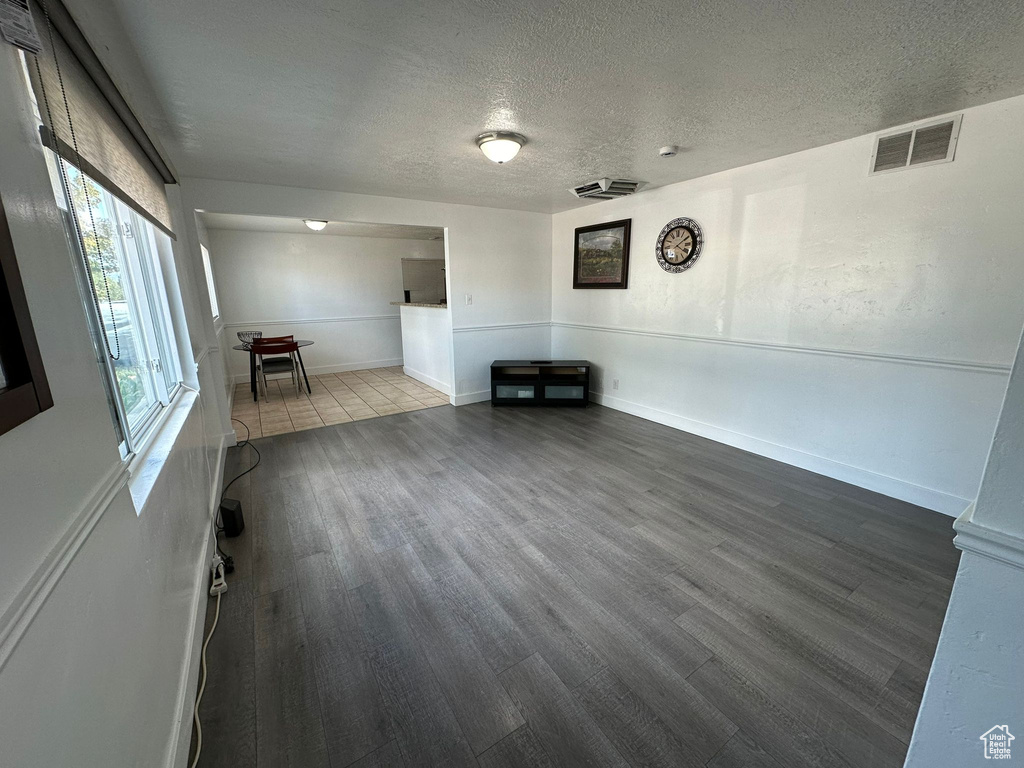 Unfurnished living room featuring a textured ceiling and hardwood / wood-style floors