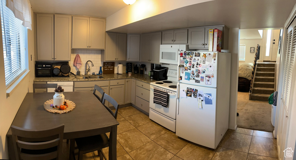 Kitchen featuring gray cabinets, white appliances, plenty of natural light, and sink