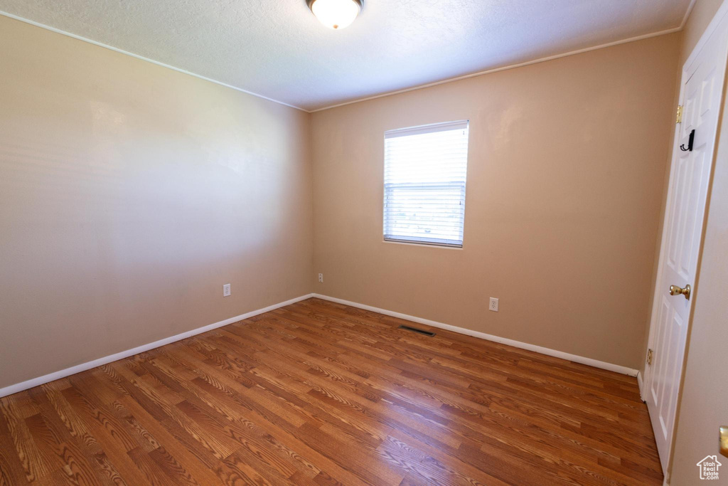 Spare room with crown molding and hardwood / wood-style floors