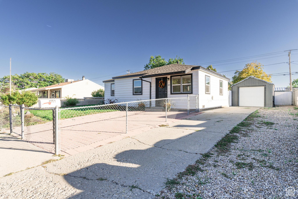 View of front of home with a garage and an outbuilding