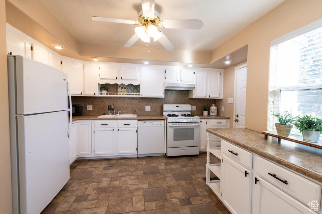 Kitchen with sink, white cabinetry, backsplash, white appliances, and ceiling fan