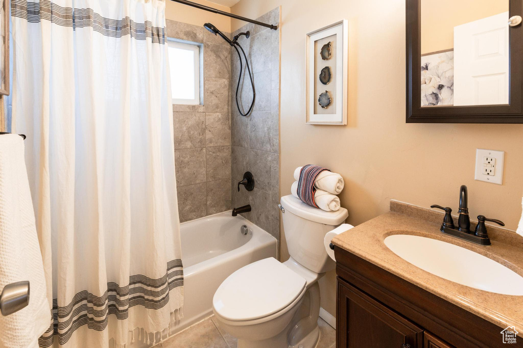 Full bathroom with tile patterned flooring, vanity, toilet, and shower / bath combo with shower curtain