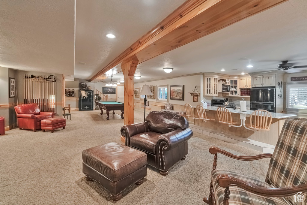 Carpeted living room with beam ceiling, pool table, and crown molding