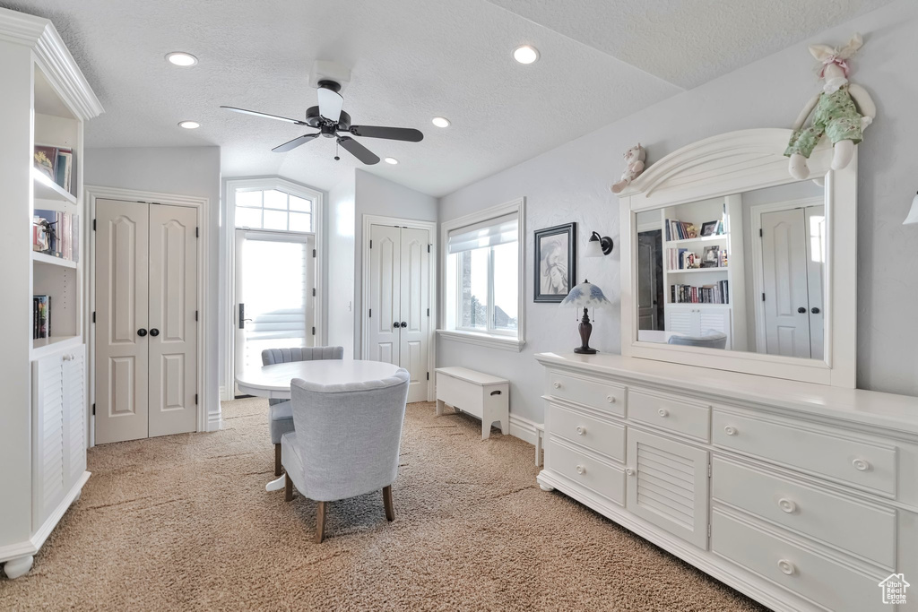 Interior space with ceiling fan, light colored carpet, a textured ceiling, and lofted ceiling