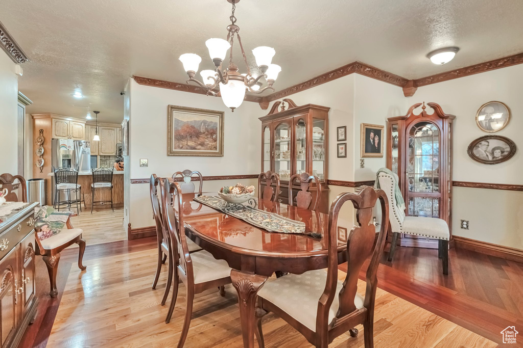 Dining space with light wood-type flooring, a textured ceiling, and a notable chandelier