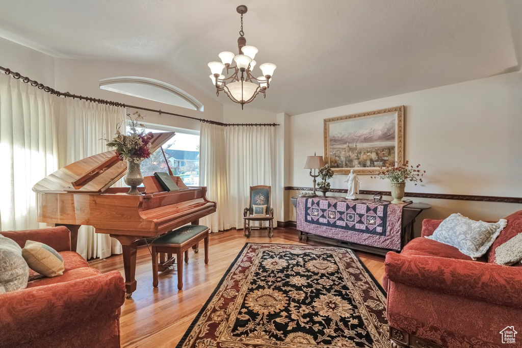 Living room featuring an inviting chandelier, light wood-type flooring, and vaulted ceiling