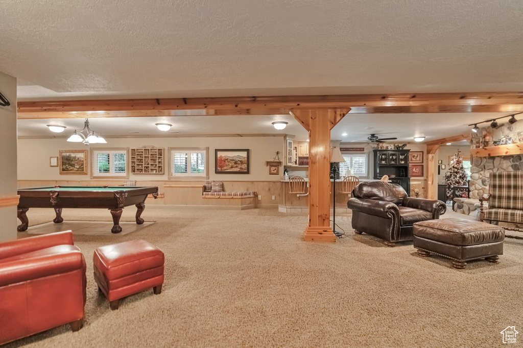 Recreation room featuring a textured ceiling, a fireplace, wooden walls, carpet, and billiards