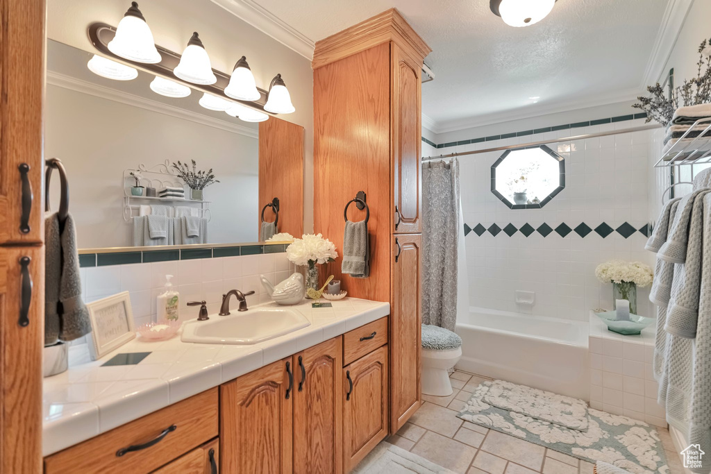 Full bathroom with shower / bathtub combination with curtain, tile patterned floors, ornamental molding, vanity, and toilet