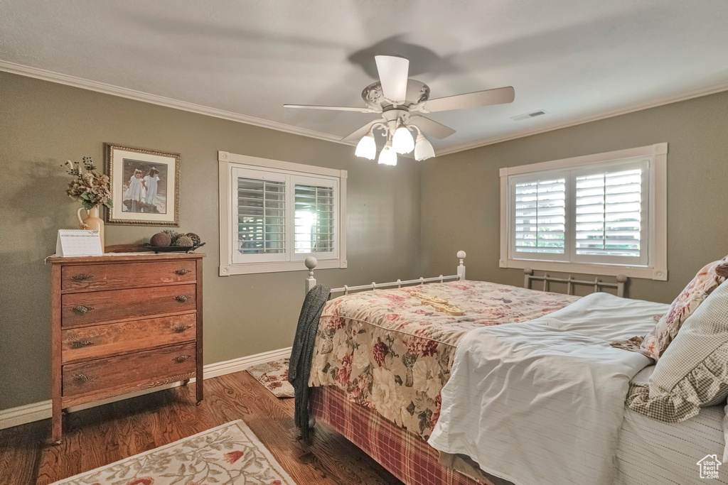 Bedroom with ceiling fan, dark wood-type flooring, and crown molding