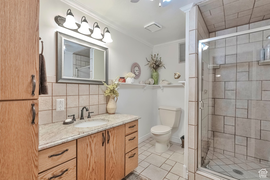 Bathroom with backsplash, a shower with shower door, vanity, and toilet