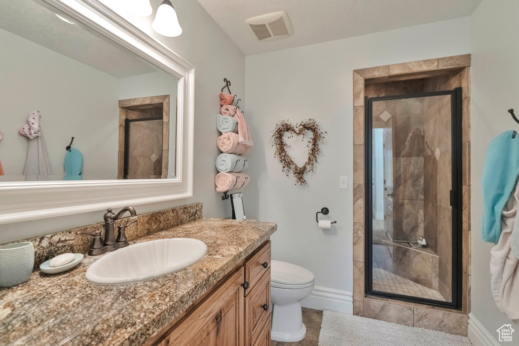 Bathroom with an enclosed shower, vanity, and toilet