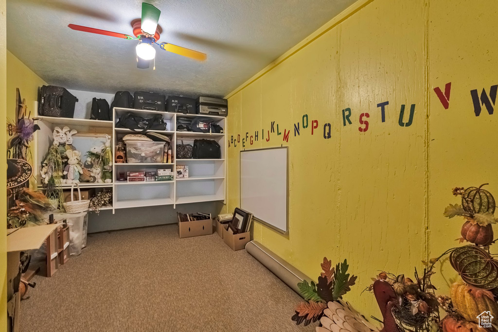 Interior space with ceiling fan, carpet floors, and a textured ceiling