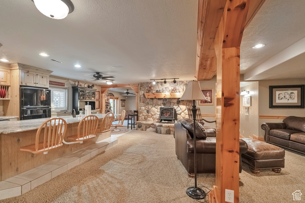 Living room with ceiling fan, light colored carpet, a fireplace, and a textured ceiling