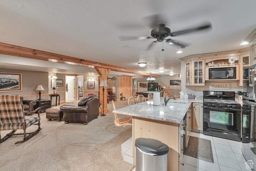 Kitchen with kitchen peninsula, black appliances, a kitchen bar, ceiling fan, and light carpet