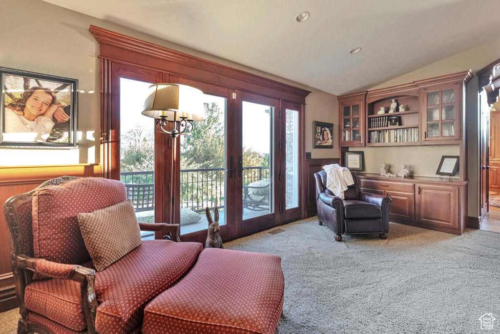 Sitting room with vaulted ceiling and light colored carpet