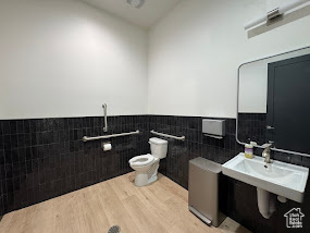 Bathroom featuring tile walls, wainscoting, and wood finished floors