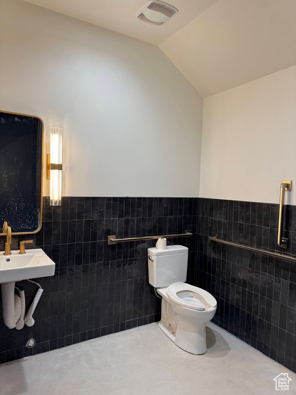 Bathroom with toilet, tile walls, and vaulted ceiling