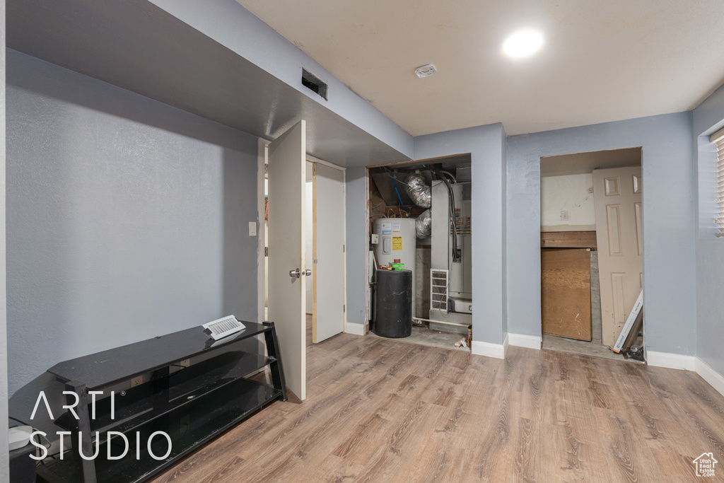 Basement featuring heating unit, water heater, and wood-type flooring